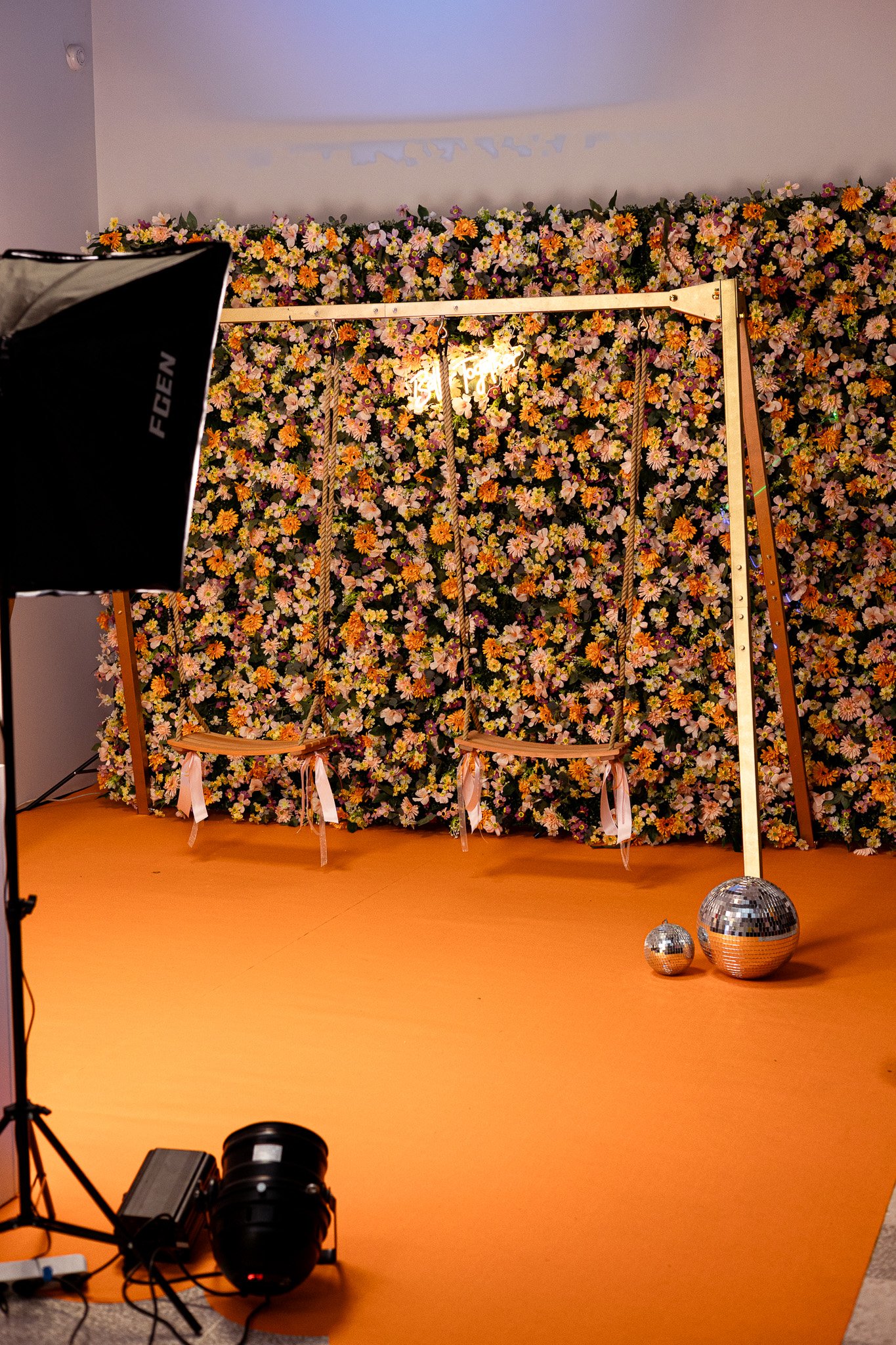 Installation d’un photocall avec balançoire, mur de fleurs et éclairage professionnel lors de la mise en place d’un décor événementiel.