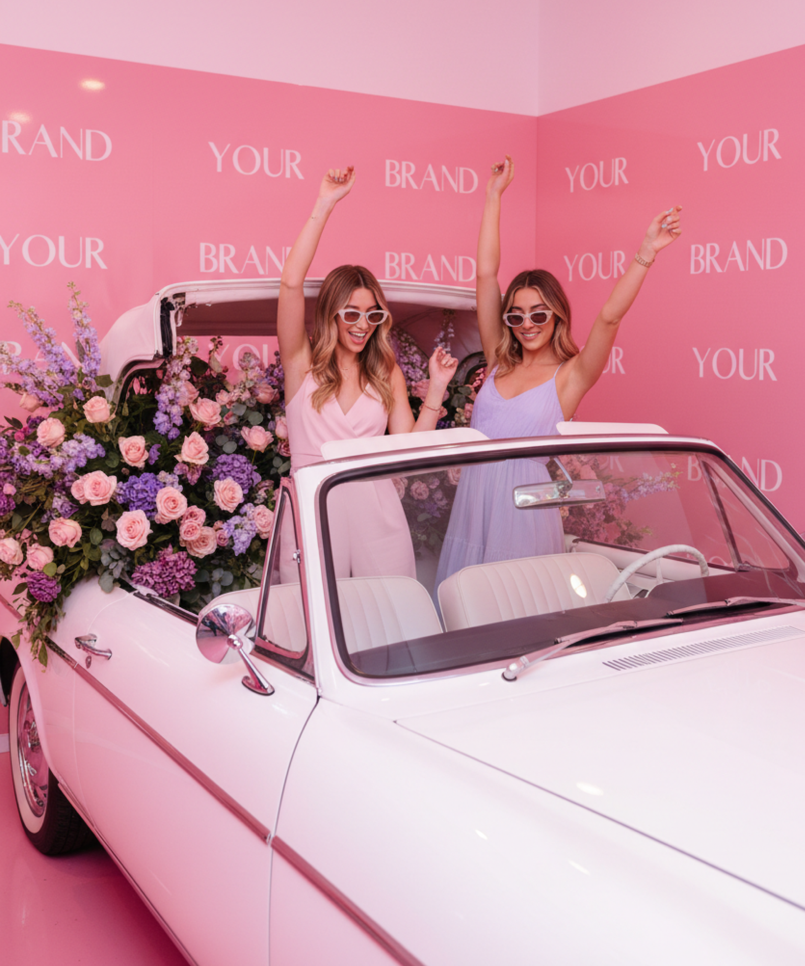 Décor événementiel sur mesure avec voiture vintage fleurie servant de photocall lors d’une activation de marque, dans un univers rose immersif et photogénique.