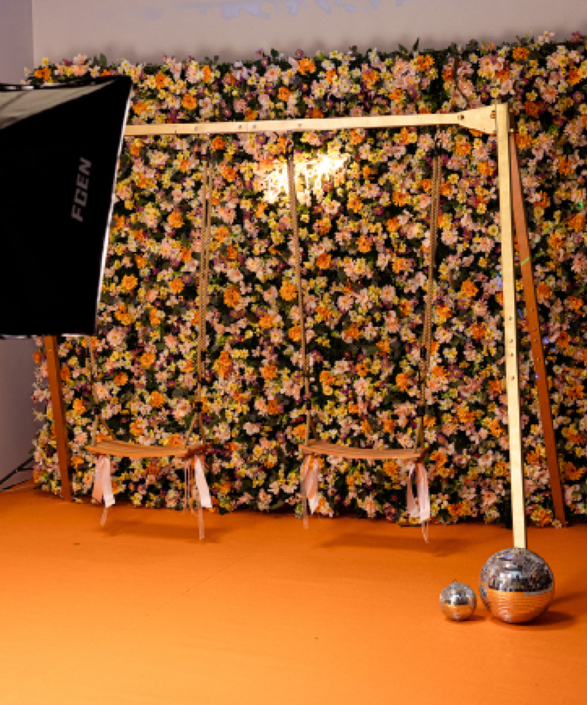 Installation d’un photocall avec balançoire, mur de fleurs et éclairage professionnel lors de la mise en place d’un décor événementiel.