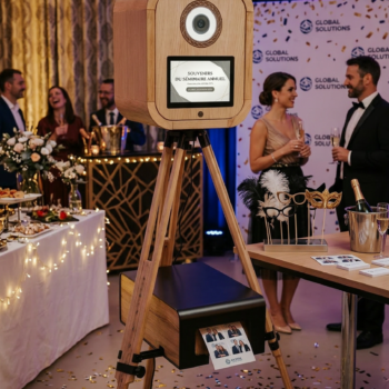 Photobooth en bois sur trépied lors d’un événement corporate avec invités en tenue élégante.