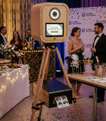 Photobooth en bois sur trépied lors d’un événement corporate avec invités en tenue élégante.